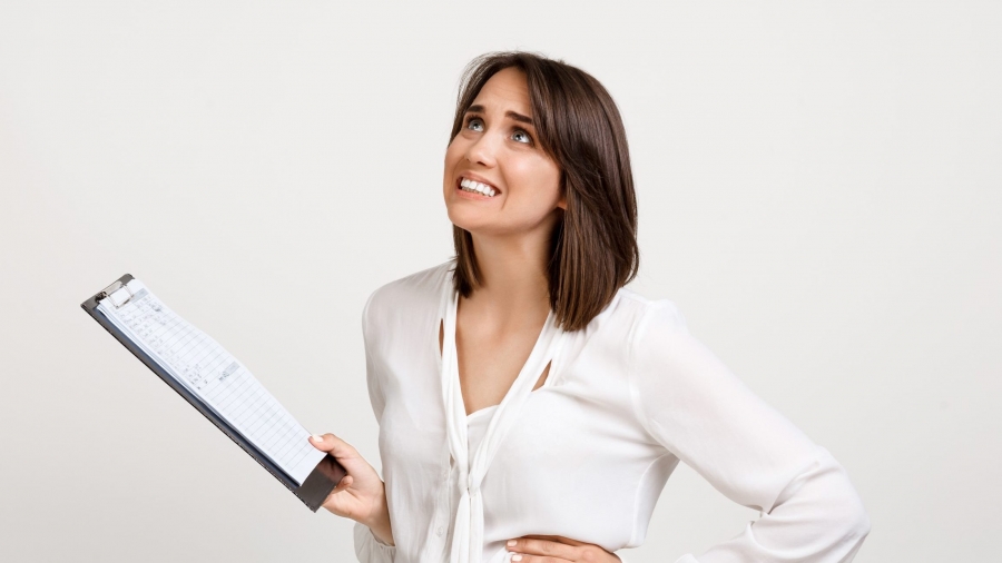 Portrait of surprised young successful business woman checking papers over white background.